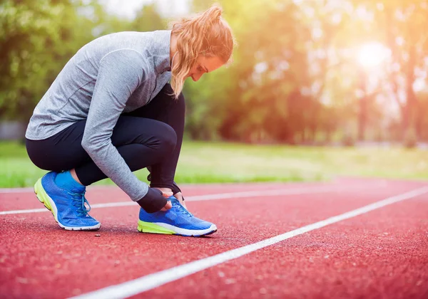 Αθλητική γυναίκα τρέχει track δένοντας Κορδόνια παπουτσιών, αξεσουάρ γυμναστικής — Φωτογραφία Αρχείου