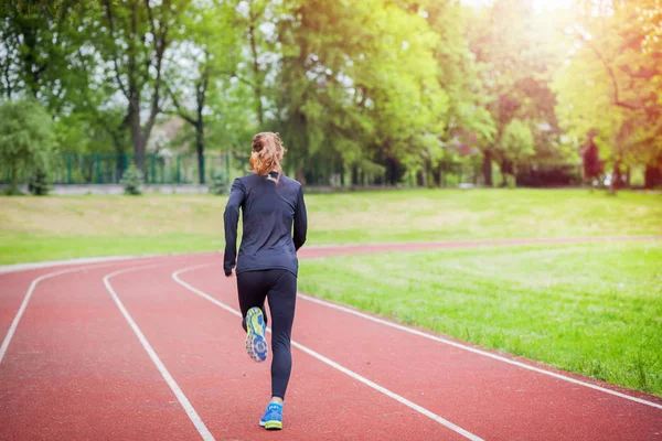 Athletic woman running on track back view, healthy lifestyle — Stock Photo, Image