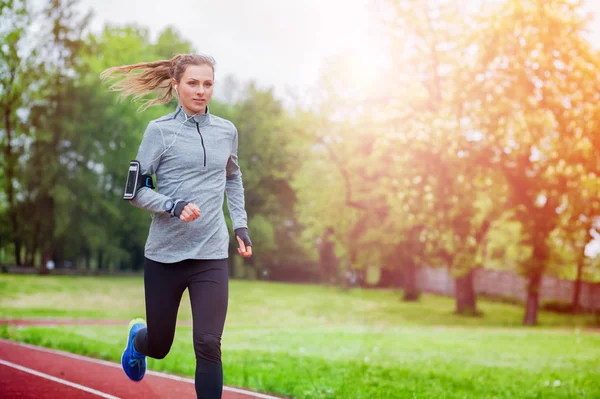 Mulher atlética correndo na pista com aplicativo de telefone inteligente e assistir, estilo de vida fitness — Fotografia de Stock