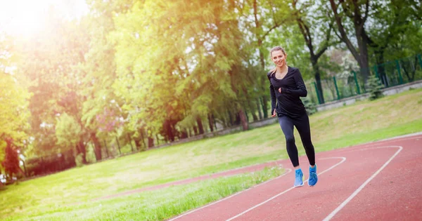 Mujer atlética corriendo en la pista, estilo de vida saludable — Foto de Stock