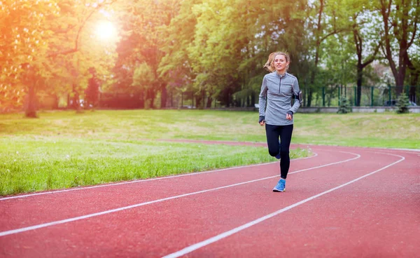 Mulher atlética correndo na pista com aplicativo de telefone inteligente, estilo de vida fitness — Fotografia de Stock