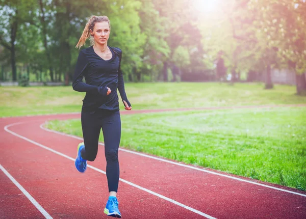 Mujer atlética corriendo en la pista, estilo de vida saludable — Foto de Stock