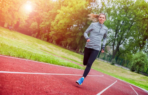 Спортивная женщина бегает на треке, здоровый образ жизни — стоковое фото