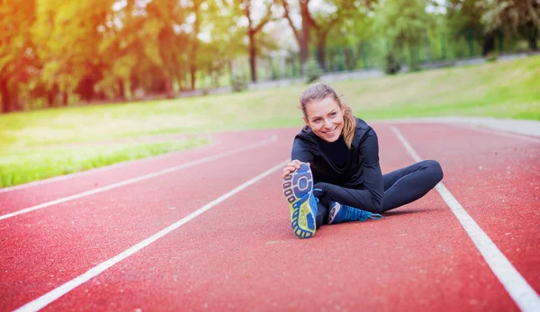 Mujer atlética estirándose en pista de atletismo antes del entrenamiento, estilo de vida saludable — Foto de Stock