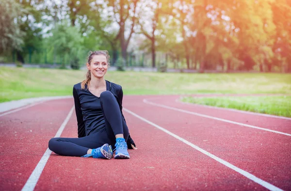 Kobieta lekkoatletycznego rozciągający się na bieżni przed szkolenia, zdrowy styl życia — Zdjęcie stockowe