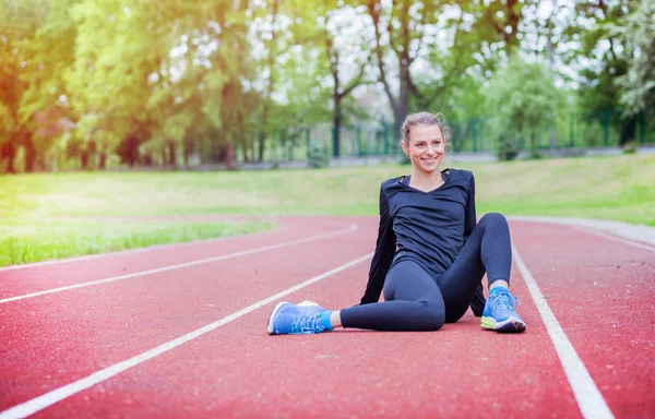 Спортивная женщина растягивается на беговой дорожке перед тренировкой, здоровый образ жизни — стоковое фото