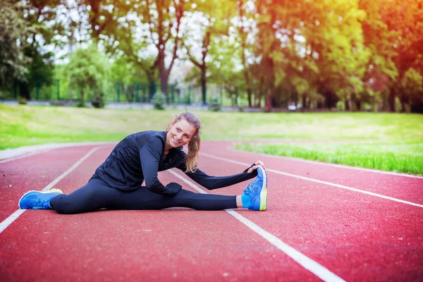 Спортивная женщина растягивается на беговой дорожке перед тренировкой, здоровый образ жизни — стоковое фото