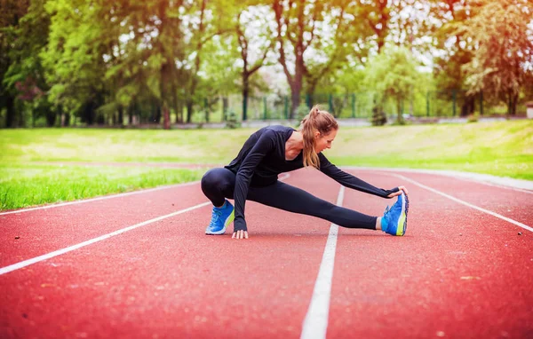 Mujer atlética estirándose en pista de atletismo antes del entrenamiento, estilo de vida saludable — Foto de Stock