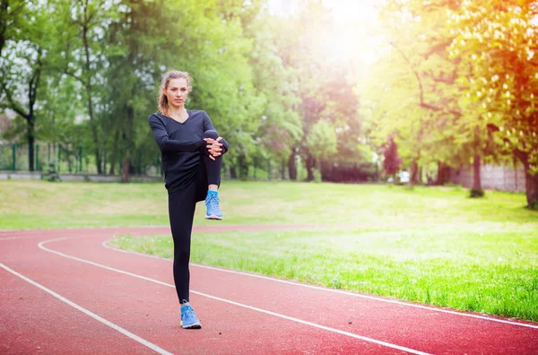 Athletic woman stretching on running track before training, healthy lifestyle — Stock Photo, Image