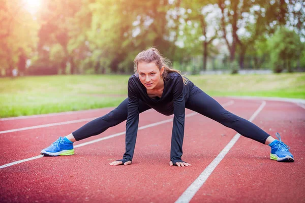 Mulher atlética que se estende na pista de corrida antes do treinamento, estilo de vida saudável — Fotografia de Stock