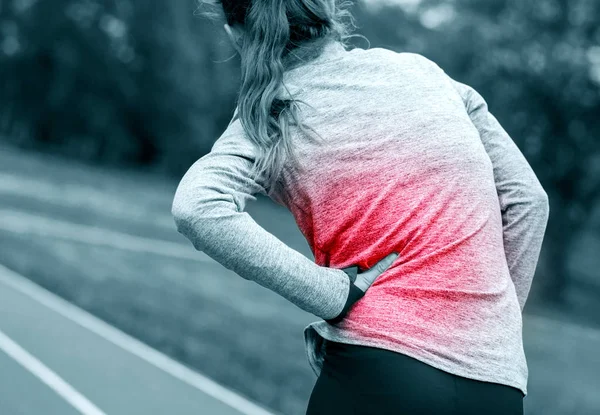 Mujer en pista de atletismo tiene calambres laterales durante el entrenamiento — Foto de Stock