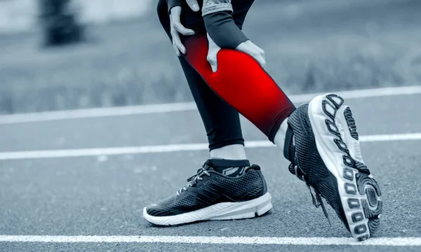 Athletic woman on running track has calf cramp and touching hurt — Stock Photo, Image