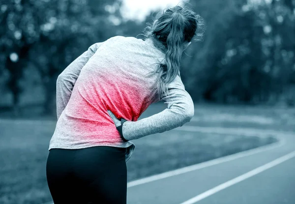 Woman on running track has side cramps during workout — Stock Photo, Image
