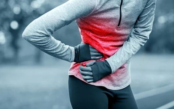 Frau auf Laufstrecke hat beim Training Seitenkrämpfe — Stockfoto