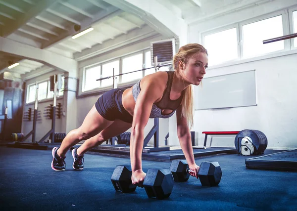 Fitness vrouw uit te werken met halters doet push ups opleiding — Stockfoto