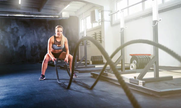 Fitness vrouw uit te werken met de slag bij touw, crossfit opleiding — Stockfoto
