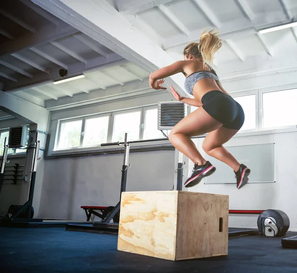 Фітнес-леді стрибає на тренувальному боксі в спортзалі — стокове фото