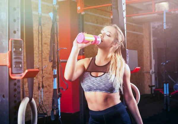 Woman drinking water at crossfit gym after training — Stock Photo, Image