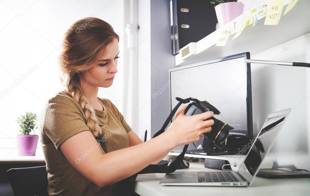 Freelance photographer woman with camera at home office editing 