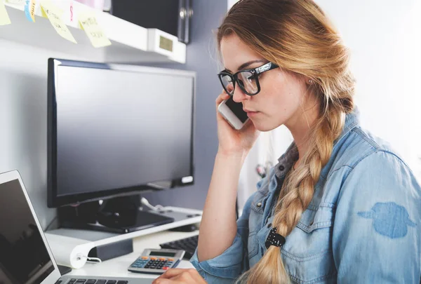 Mujer trabajando en la oficina del hogar mientras habla por teléfono — Foto de Stock