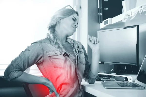 Frau im Home Office leidet unter Rückenschmerzen, wenn sie am Computertisch sitzt — Stockfoto