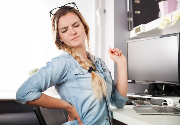 Woman in home office suffering from backache sitting at computer desk — Stock Photo, Image