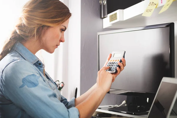 Woman at home office using calculator, calculating budget — Stock Photo, Image