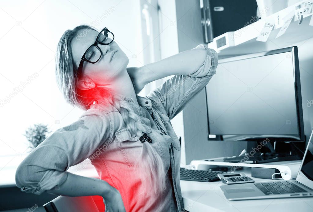 Woman in home office suffering from backache sitting at computer desk