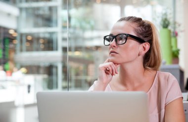 Laptop ile çalışma ve açık alan Bürosu'nda modern iç gelecek hakkında düşünme iş kadını