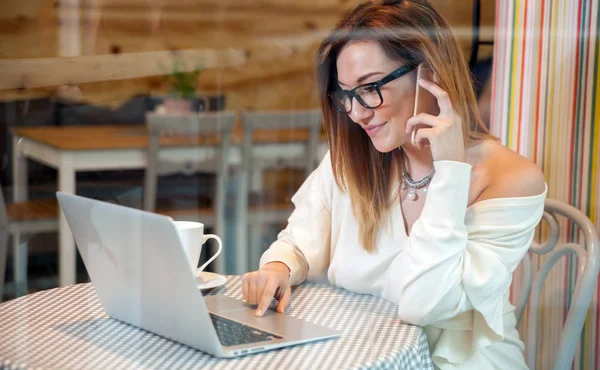 Mulher de negócios trabalhando com laptop e telefone celular no café, conceito freelance — Fotografia de Stock
