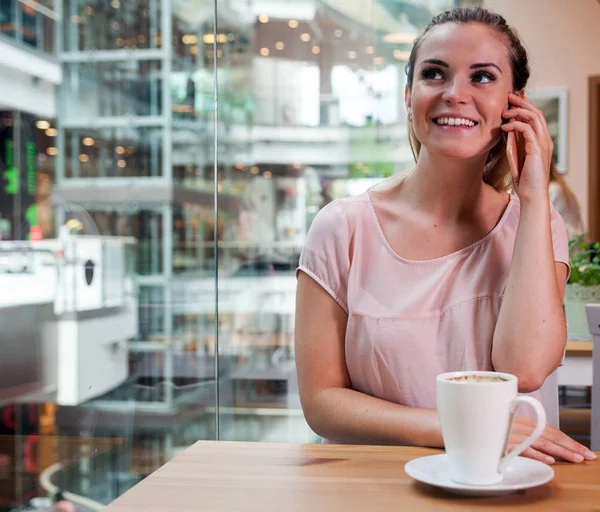 Girl talking on mobile phone in cafe at shopping mall — Stock Photo, Image