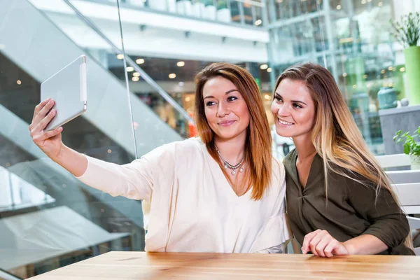 Twee meisjes van de vrouw nemen selfie met digitale tablet in café bij winkelcentrum — Stockfoto