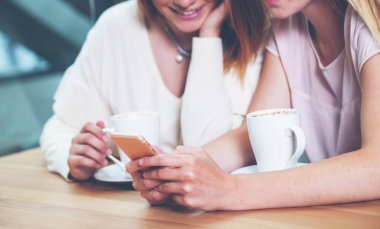 İki arkadaş kızlar cep telefonuyla ve medya içeriği izlerken Cafe