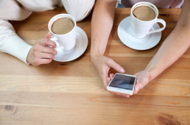 Cep telefonu kullaranarak ve medya içeriği, izlerken kafede iki arkadaş kızlar yakın çekim