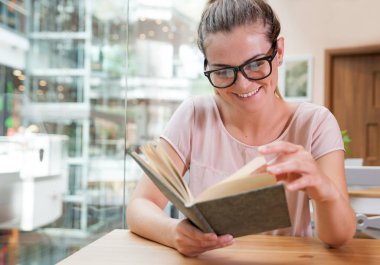 Rahat gülümseyen kız okuma kitabı café'de alışveriş merkezi