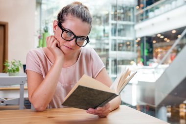 Rahat gülümseyen kız okuma kitabı café'de alışveriş merkezi