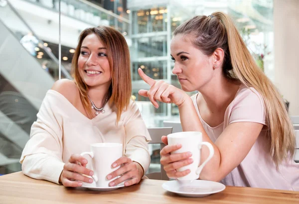 Smiling friends girls pointing at something in shopping mall cafe — Stock Photo, Image