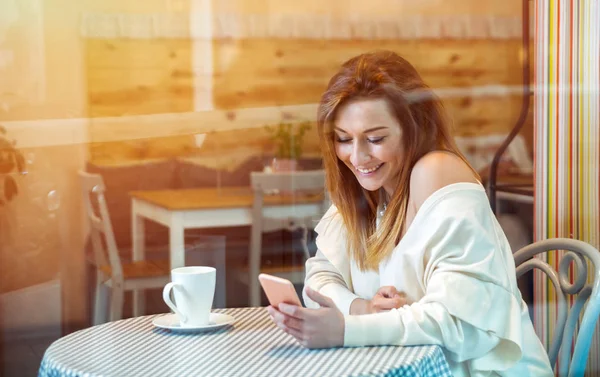 Mujer sola riendo y mensajes de texto con teléfono móvil en la cafetería —  Fotos de Stock