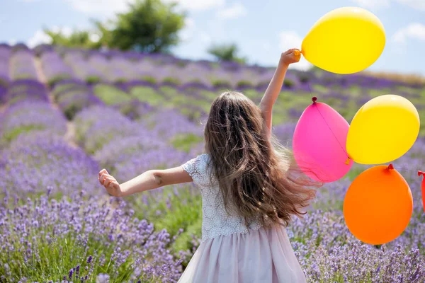 Mooi kind meisje loopt met kleurrijke ballonnen in Lavendel veld zomer vrijheid concept — Stockfoto