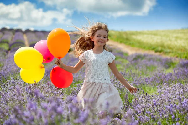 Jolie fille enfant court avec des ballons colorés dans le champ de lavande concept de liberté d'été — Photo