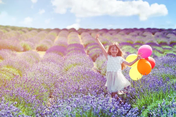 Krásné dítě dívka utíká s barevné balónky levandulové pole letní svobodu koncepce — Stock fotografie