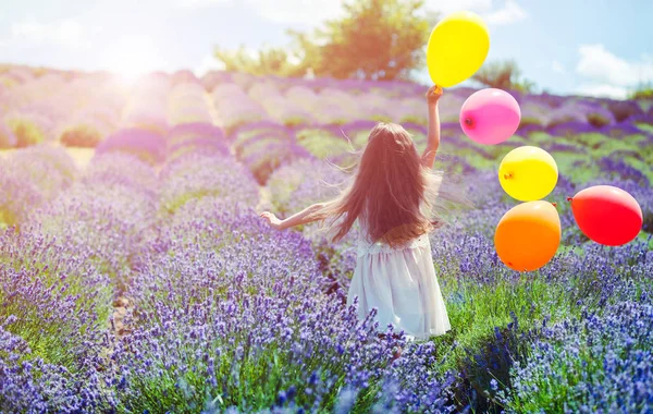 Linda niña corre con globos de colores en el campo de lavanda concepto de libertad de verano — Foto de Stock