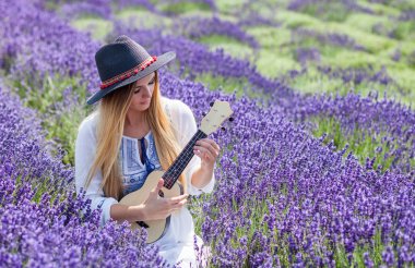 Boho kız ukulele lavanta alanında yaz gününde, hippi moda stil oynamaktan