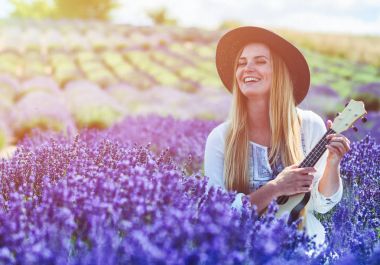 Boho kız ukulele lavanta alanında yaz gününde, hippi moda stil oynamaktan