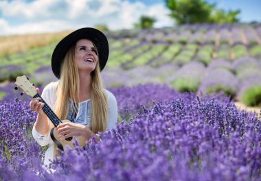 Boho kız ukulele lavanta alanında yaz gününde, hippi moda stil oynamaktan