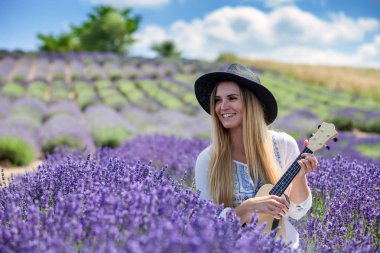 Boho kız ukulele lavanta alanında yaz gününde, hippi moda stil oynamaktan