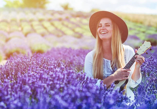 Boho kız ukulele lavanta alanında yaz gününde, hippi moda stil oynamaktan