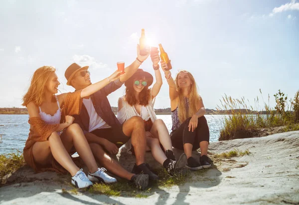 Друзья веселятся и пьют на пляже, позитивное настроение — стоковое фото