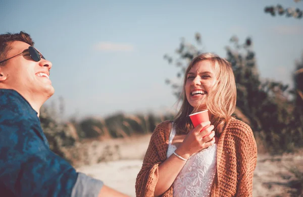 Happy couple sitting at the beach and drinking, love and friendship — Stock Photo, Image