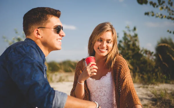 Pareja feliz sentada en la playa y bebiendo, amor y amistad — Foto de Stock